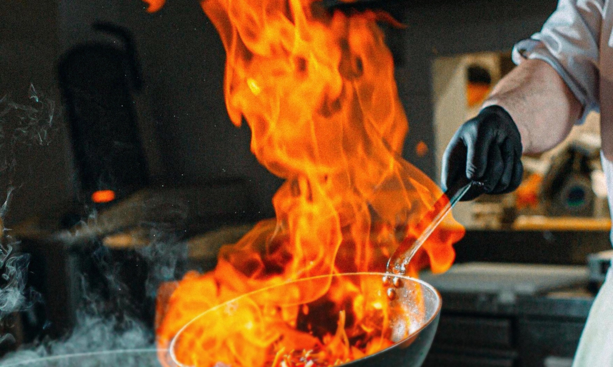 Un chef tient un wok enflammé